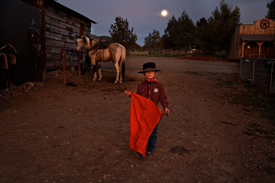 Ready for action with his red cape, sheriff's badge and mustang Paiute, a young boy stands under the full moon at the Lauman ranch.