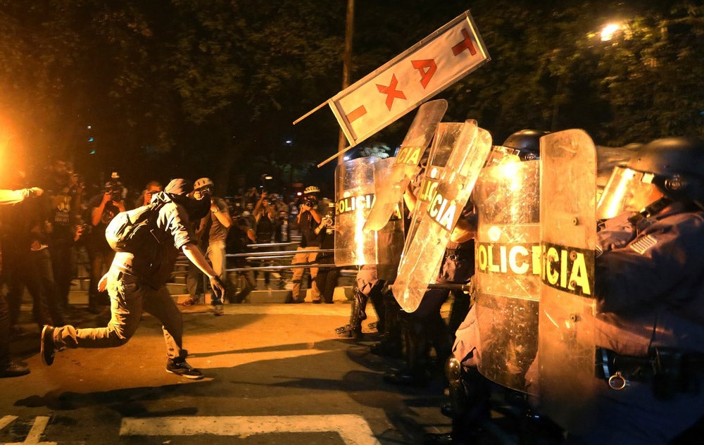 A demonstrator from the group called Black Bloc throws a taxi sign at military policemen during a protest against Sao Paulo State Governor Geraldo Alckmin, in Sao Paulo August 3, 2013.  REUTERS/Nacho Doce (BRAZIL  - Tags: CIVIL UNREST POLITICS TPX IMAGES OF THE DAY)   - RTX1291W