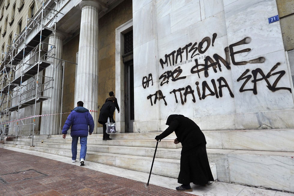 This image of an elderly women begging in front of a Greek bank was captured by AFP stringer Louisa Gouliamaki. The graffiti on the side of the bank reads “Cops, your children will eat you.”