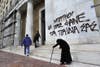 This image of an elderly women begging in front of a Greek bank was captured by AFP stringer Louisa Gouliamaki. The graffiti on the side of the bank reads “Cops, your children will eat you.”