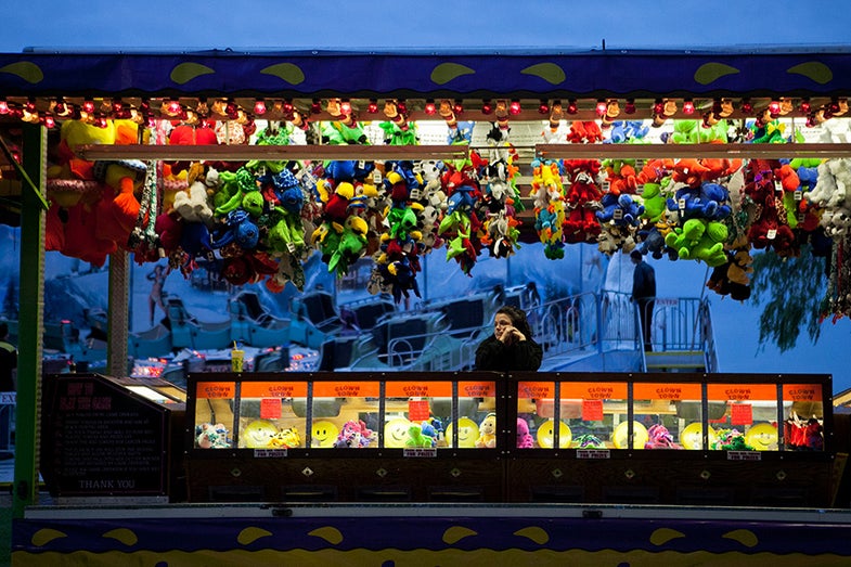 At each carnival location, workers are usually assigned to a specific ride, food stall, or game for the week’s duration. As night falls, a carnival worker waits for visitors to play her game. When the carnival is open, workers usually attend to rides or games from noon until midnight.