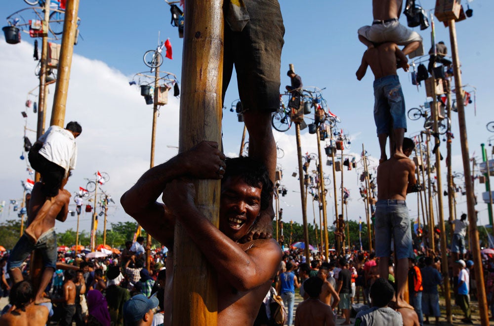Participants react as they struggle during a greased pole climbing competition held as part of Indonesia's 68th Independence Day celebration, at Ancol Dream Park in Jakarta, August 17, 2013. REUTERS/Beawiharta (INDONESIA - Tags: SOCIETY ANNIVERSARY) - RTX12OO3