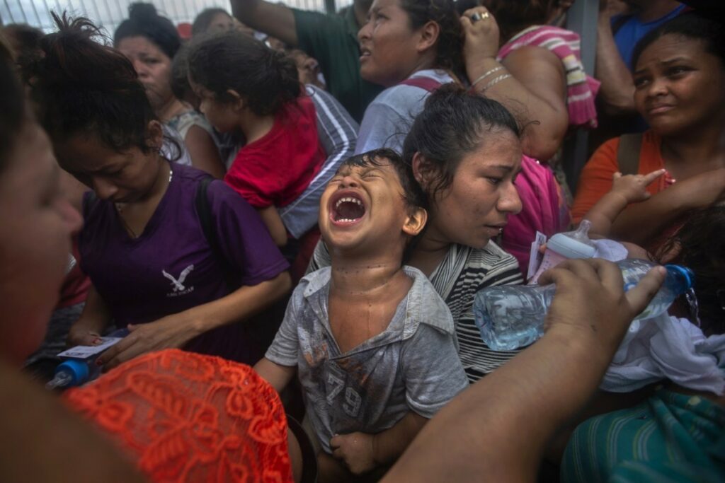 Migrant child screaming in a crowd
