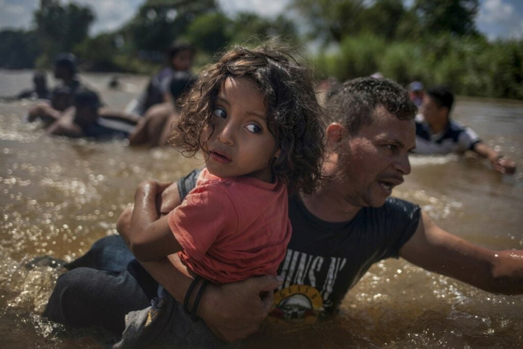 child being carried across shallow water