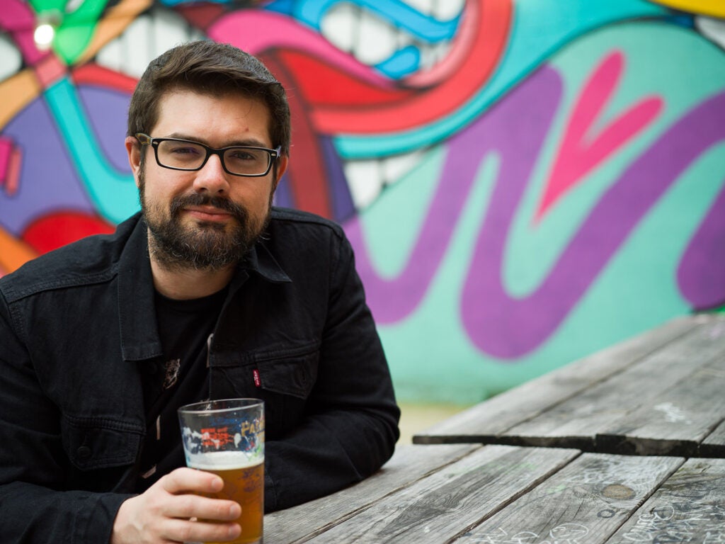 man with beer in front of graffiti