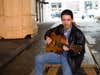 Man sitting on picnic table and playing guitar