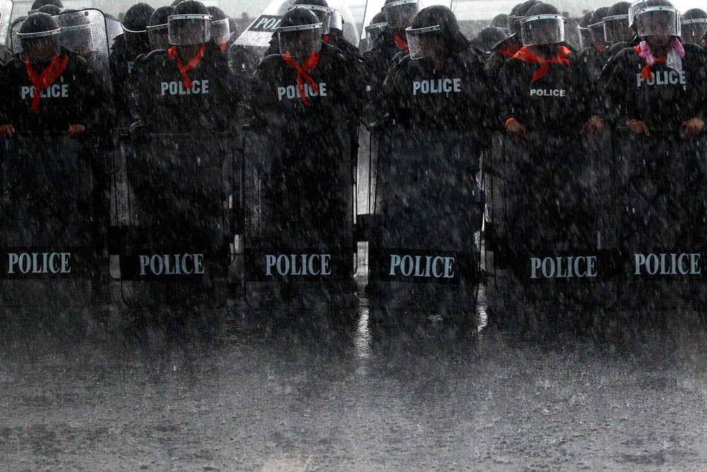 Heavy rain falls on policemen taking positions as rubber farmers protest near the airport in Surat Thani September 4, 2013. Tens of thousands of Thai rubber farmers protesting against a sharp drop in prices escalated protests across southern Thailand on Wednesday, cutting off access to large swathes of the region by blocking roads leading to tourist and commercial hubs.   REUTERS/Athit Perawongmetha (THAILAND - Tags: BUSINESS CIVIL UNREST POLITICS AGRICULTURE TPX IMAGES OF THE DAY) - RTX136ZE