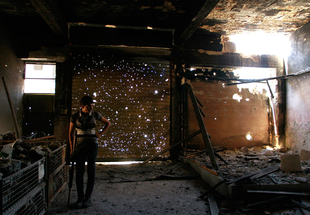 A Free Syrian Army fighter holds his weapon as he stands inside a burned shop in Aleppo's Karm al-Jabal district July 23, 2013. REUTERS/Hamid Khatib (SYRIA - Tags: CONFLICT MILITARY CIVIL UNREST TPX IMAGES OF THE DAY) - RTX11VYK
