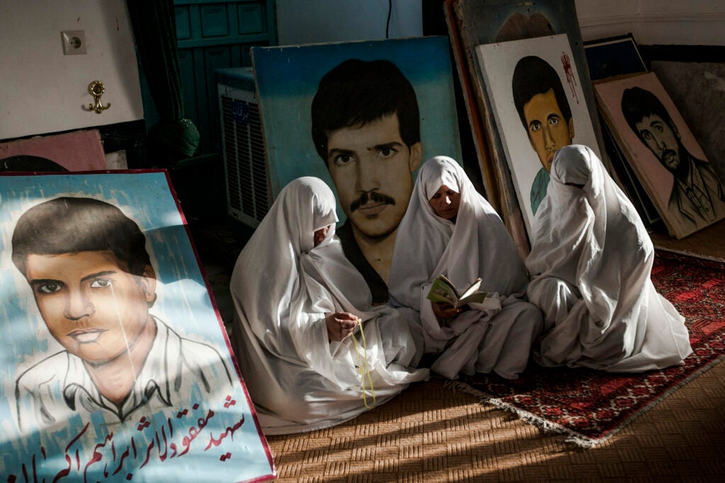 The mother of Martyrs, those who died in the Iran-Iraq war, praying at the graves of their sons and surrounded by their portraits.