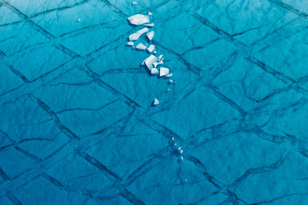 Shards of ice float in a seasonal meltwater lake atop the Greenland ice sheet, 70 miles east of Ilulissat, 2014. From the series, <em>Greenland</em>.