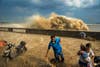 Visitors run away as waves from a tidal bore surge past a barrier on the banks of Qiantang River, in Hangzhou Zhejiang province, August 24, 2013. Picture taken August 24, 2013. REUTERS/Stringer (CHINA - Tags: ENVIRONMENT TPX IMAGES OF THE DAY) CHINA OUT. NO COMMERCIAL OR EDITORIAL SALES IN CHINA - RTX12VNG