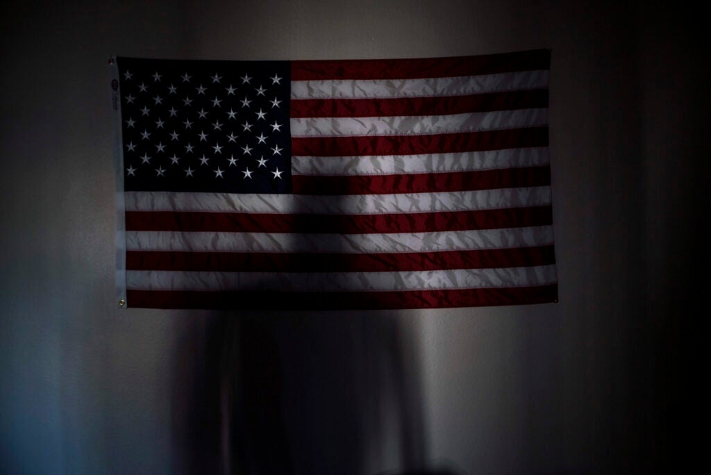 Manny Bojorquez casts a shadow on a flag in his apartment in Mesa, Arizona. He was a member of the 2/7 Marines, which fought in Afghanistan in 2008 and now has a suicide rate more than 10 times higher than the national average. Since the deployment, there have been 14 suicides. Bojorquez, like many of his comrades, has been haunted by the high number of deaths in his battalion and even tried to shoot himself. He has tried to get counseling from the VA, but walked out of a session when he was told to treat the loss of his friends like a bad break up with a girlfriend. The Marines of the 2/7 have since created a database of their members to help stem the suicides by sending the nearest Marine to check on someone who is suicidal. Photographed on Friday, March 27, 2015.