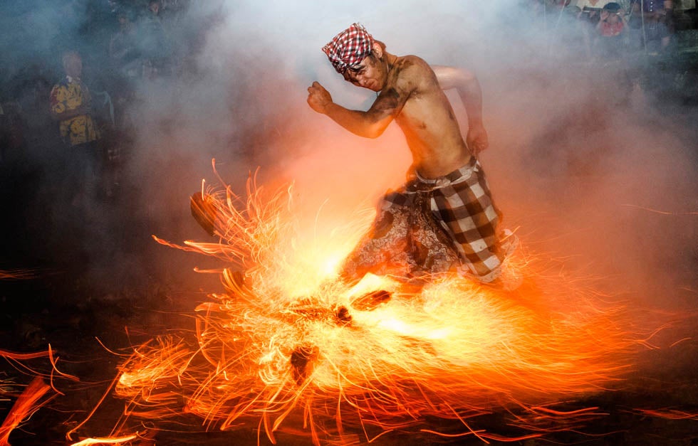 A Balinese man kicks up fire during the "Perang Api" ritual in Indonesia. The ritual occurs before Nyepi Day, a day of silence for self-reflection to celebrate the Balinese Hindu New Year, where Hindus in Bali observe meditation and fasting.