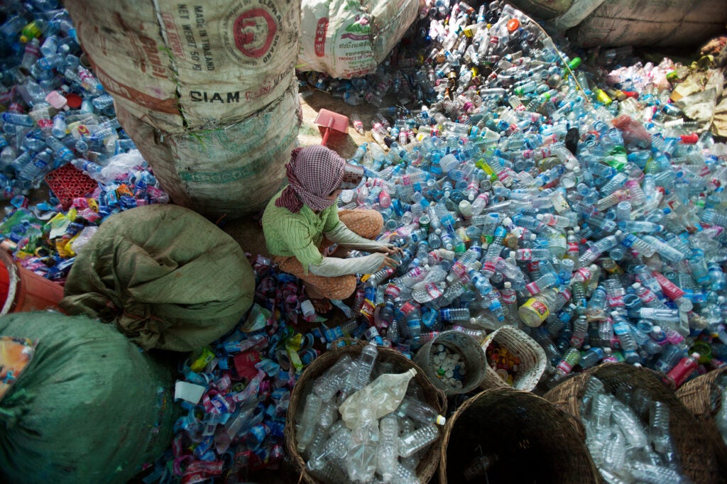 Sorting plastic drinks bottles; white caps are put into one bucket, color caps into another, grey, blue and clear bottles are put into different containers, and the plastic wrappers to one side; everything has its place. From the series <em>Smokey Mountain and Recycling Phnom Penh</em>, 2007-2010.