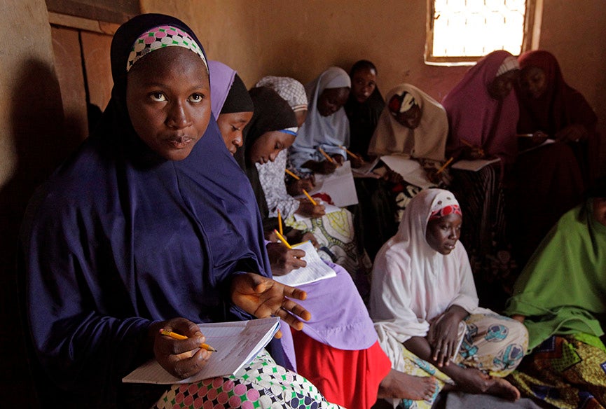 In this Monday, June 2, 2014 photo, Maimuna Abdullahi, left, writes down information from the blackboard as she and others attend school in Kaduna, Nigeria. Maimuna wore the scars of an abused woman anywhere: A swollen face, a starved body, and, barely a year after her wedding, a divorce. But for Maimuna, it all happened by the time she was 13. Maimuna is one of thousands of divorced girls in Nigeria who were married as children and then got thrown out by their husbands or simply fled. Sunday Alamba is based in Lagos, Nigeria. More of his work can be seen <a href="http://sundayalamba.com/">here. </a>
