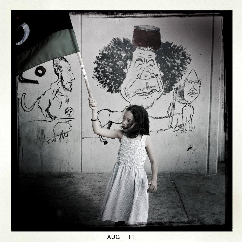 A young girl holds up a Libyan flag at a rebel checkpoint in Tripoli, Libya on Aug. 29, 2011.