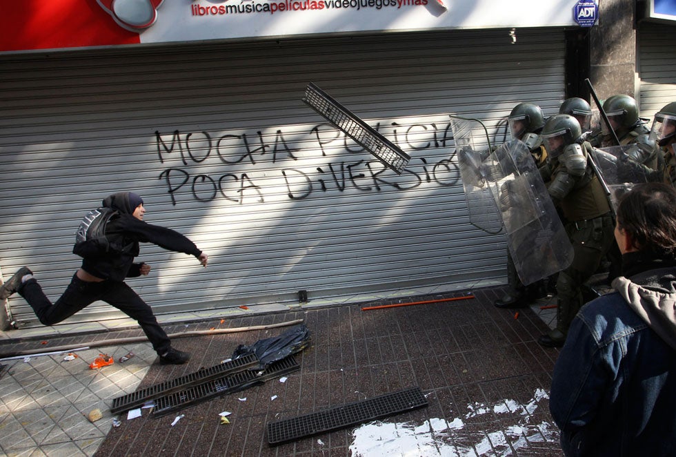 A demonstrator throws a grill at riot policemen during a rally in Santiago, Chile. The graffiti says "Many policemen, little fun." Ivan Alvarado is a Reuters staff photographer based in Chile. See more of his work on the <a href="http://blogs.reuters.com/ivan-alvarado/">Reuters blog</a>.