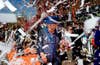 Queen Beatrix of the Netherlands is greeted by a cheering crowd and ticker tape in the city of Veenendaal , during a parade to celebrate the annual Queens' day holiday.