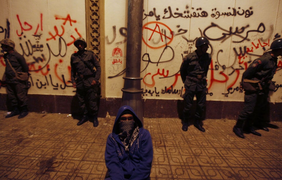 A masked anti-Mursi protester sits near Republican Guard soldiers in front of the presidential palace in Cairo, Egypt. Amr Dalsh is a Reuters staffer based in Cairo, Egypt, who has been with the organization since 2006.