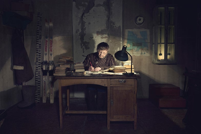 Slava in his office writes down the collected data in the journal after his observations on the meteorological field outside.