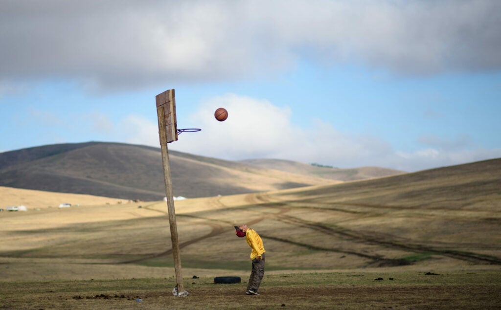 Purevsurengiin Togtokhsuren plays basketball after taking care of the horses in Khui Doloon Khudag, some 50 kms west of Ulan Bator on July 8, 2015.