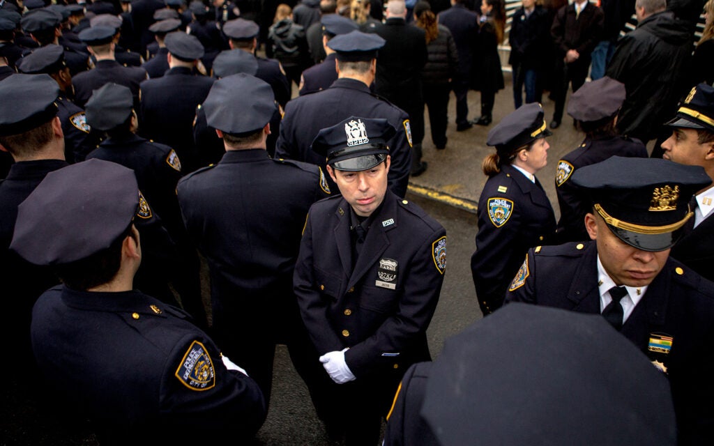 "Thousands of officers from the NYPD and police departments across the country assembled in Brooklyn to lay murdered officer Wenjian Liu to rest… and to protest Mayor Bill De Blasio. The majority of cops attending the service turned their backs on outdoor screens showing the mayor as he addressed mourners inside the funeral home. This officer is one of a handful of officers who didn’t take part in the demonstration."