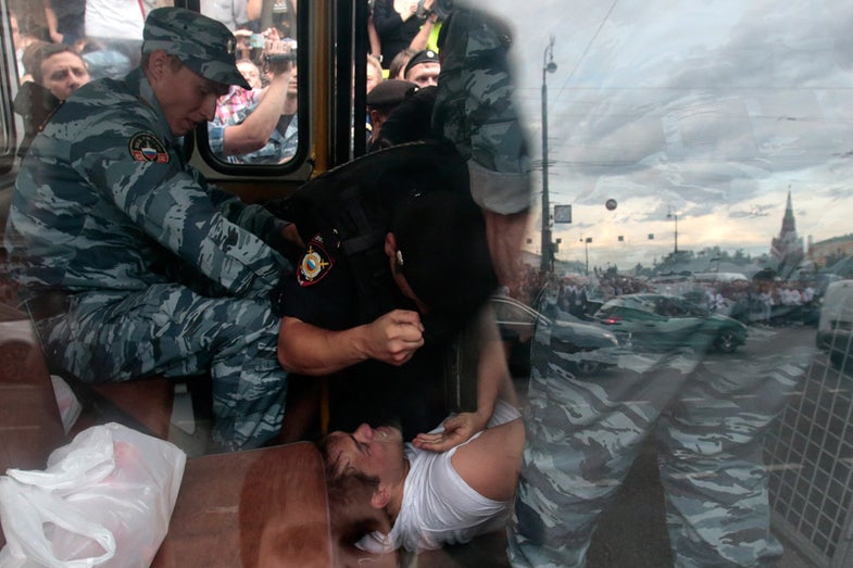 A policeman beats a man who was detained inside a police bus during a protest against the verdict of a court in Kirov, which sentenced Russian opposition leader Alexei Navalny to five years in jail, in central Moscow, July 18, 2013. Russian opposition leader Alexei Navalny was sentenced to five years in jail for theft on Thursday, an unexpectedly tough punishment which supporters said proved President Vladimir Putin was a dictator ruling by repression. REUTERS/Tatyana Makeyeva (RUSSIA - Tags: POLITICS CIVIL UNREST CRIME LAW) - RTX11R0E