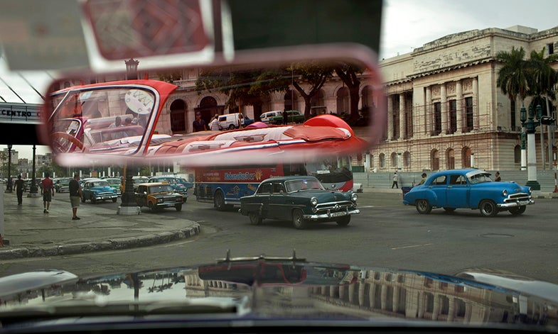 In this Oct. 16, 2014 photo, people drive classic American car in Old Havana, Cuba. These classic cars are now part of Havana’s tourist draw. That’s allowed many to paint and polish their aging vehicles. (AP Photo/Franklin Reyes)
