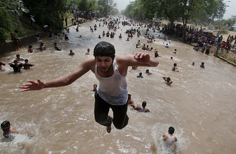 A boy jumps as people cool themselves off in a canal in Lahore, Pakistan, where temperature reached 46 degrees Celsius (114.8 Fahrenheit) on Sunday, June 8, 2014. Many cities in Pakistan are facing heat wave conditions with temperatures reaching 50 degrees Celsius (122 Fahrenheit) in some places. (AP Photo/K.M. Chaudary)