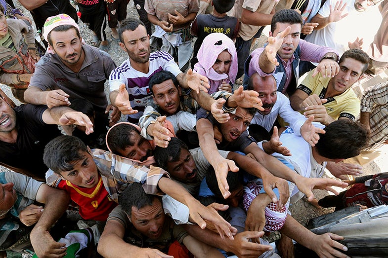 Displaced Iraqis from the Yazidi community gather for humanitarian aid at the Syria-Iraq border at Feeshkhabour border point, northern Iraq, Sunday, Aug. 10, 2014. Kurdish authorities at the border believe some 45,000 Yazidis passed the river crossing in the past week and thousands more are still stranded in the mountains. (AP Photo/ Khalid Mohammed)