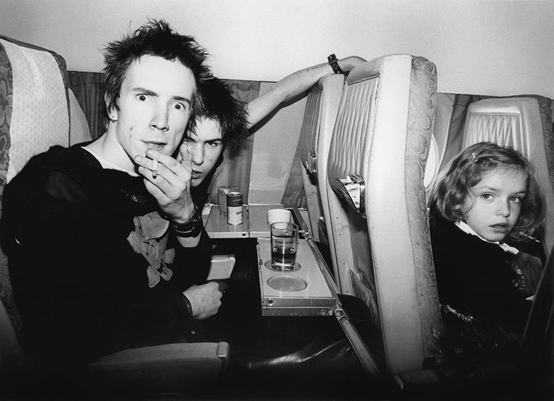 Johnny Rotten and Sid Vicious of The Sex Pistols on plane with an unknown little girl, flying from London to Brussels. November 1977. © Bob Gruen / www.bobgruen.com Please contact Bob Gruen's studio to purchase a print or license this photo. email: websitemail01@aol.com phone: 212-691-0391