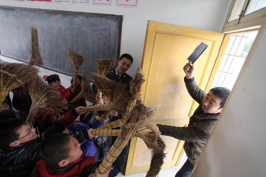 Students practice defending themselves with brooms as a soldier observes during an anti-violence exercise at a primary school in Rugao, Jiangsu province, China.