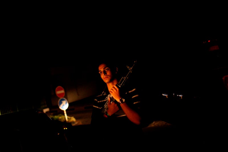 A man patrols his neighborhood after celebrating Iftar, when Muslims break their fast during Ramadan, in Tripoli, Libya, Aug. 27, 2011.