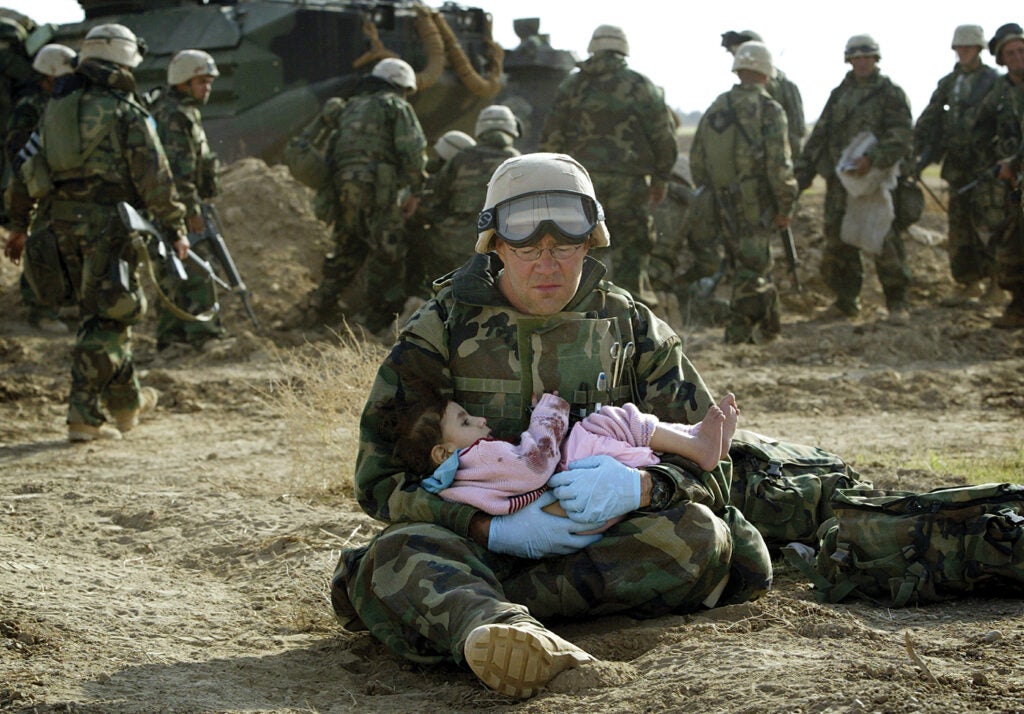 U.S. Marine holds Iraqi child after crossfire ripped apart family in central Iraq. From: <em>War is Beautiful</em> by David Shields, published by powerHouse Books.