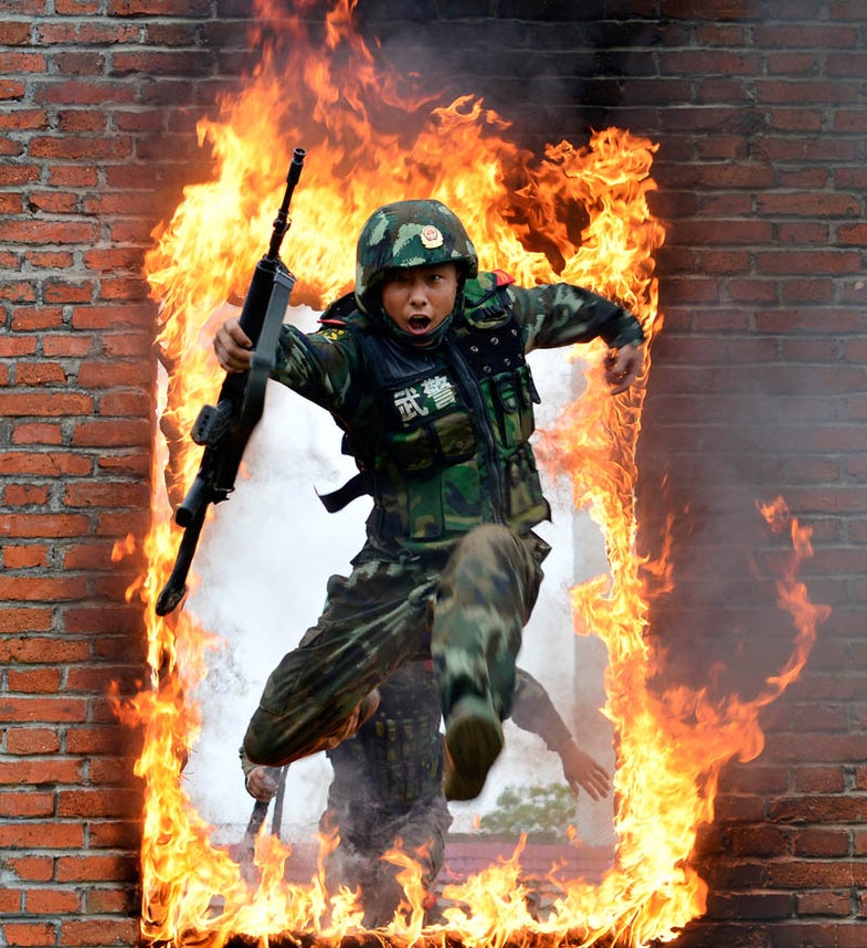 A paramilitary policeman jumps through a fire barrier during a military training exercise in Chuzhou, Anhui province, July 22, 2013. Picture taken July 22, 2013. REUTERS/China Daily (CHINA - Tags: MILITARY TPX IMAGES OF THE DAY) CHINA OUT. NO COMMERCIAL OR EDITORIAL SALES IN CHINA - RTX11VQN