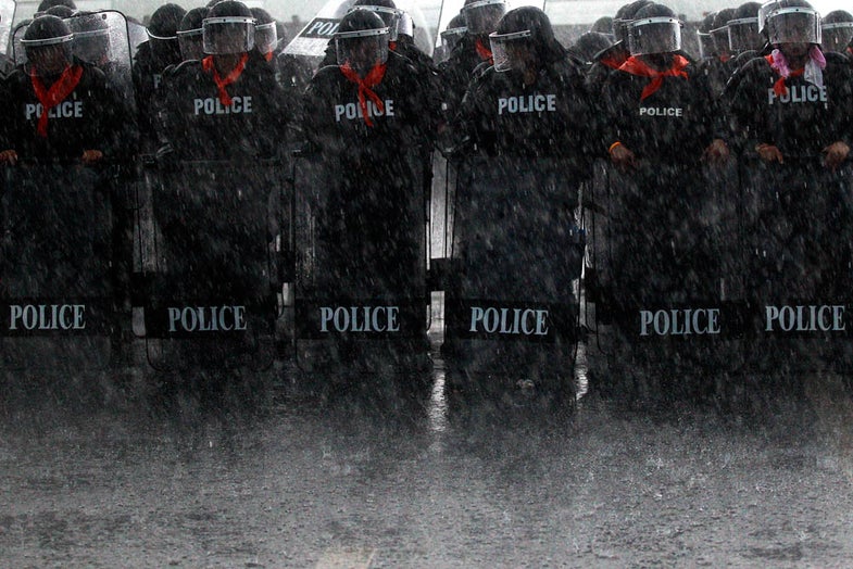 Heavy rain falls on policemen taking positions as rubber farmers protest near the airport in Surat Thani September 4, 2013. Tens of thousands of Thai rubber farmers protesting against a sharp drop in prices escalated protests across southern Thailand on Wednesday, cutting off access to large swathes of the region by blocking roads leading to tourist and commercial hubs. REUTERS/Athit Perawongmetha (THAILAND - Tags: BUSINESS CIVIL UNREST POLITICS AGRICULTURE TPX IMAGES OF THE DAY) - RTX136ZE