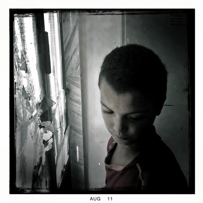 A child stands in front of a shattered window after a firefight between rebel fighters and forces loyal to Col. Muammar el-Qaddafi, Tripoli, Libya on Aug. 30, 2011.