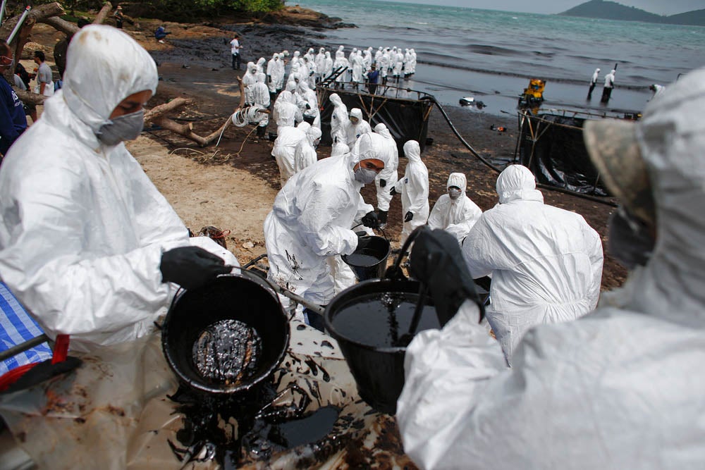 Thai soldiers in white biohazard suits take part in a clean-up operation at Ao Prao Beach on Koh Samet, Rayong July 30, 2013. Crude oil that leaked from a pipeline in the Gulf of Thailand over the weekend has reached a Thai tourist resort, pipeline operator PTT Global Chemical Pcl said on Monday. Around 50,000 litres of crude oil poured into the sea on Saturday around 20 km (12 miles) off the coast of Rayong, southeast of the capital Bangkok. REUTERS/Athit Perawongmetha (THAILAND - Tags: DISASTER ENVIRONMENT TPX IMAGES OF THE DAY) - RTX124II