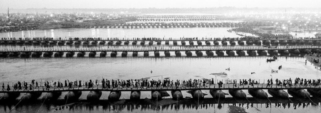 ALLAHABAD, INDIA - FEBRUARY 09: (EDITORS NOTE: Image was created using an iPhone panoramic application) Hindu pilgrims make their way over pontoon bridges near Sangam, the confluence of the holy rivers Ganges, Yamuna and the mythical Saraswati, during the Maha Kumbh Mela on February 9, 2013 in Allahabad, India. The Maha Kumbh Mela, believed to be the largest religious gathering on earth is held every 12 years on the banks of Sangam, the confluence of the holy rivers Ganga, Yamuna and the mythical Saraswati. The Kumbh Mela alternates between the cities of Nasik, Allahabad, Ujjain and Haridwar every three years. The Maha Kumbh Mela celebrated at the holy site of Sangam in Allahabad, is the largest and holiest, celebrated over 55 days, it is expected to attract over 100 million people. (Photo by Daniel Berehulak/Getty Images)