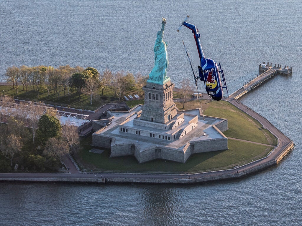 Red Bull Helicopter mid barrel roll near the Statue of Liberty.