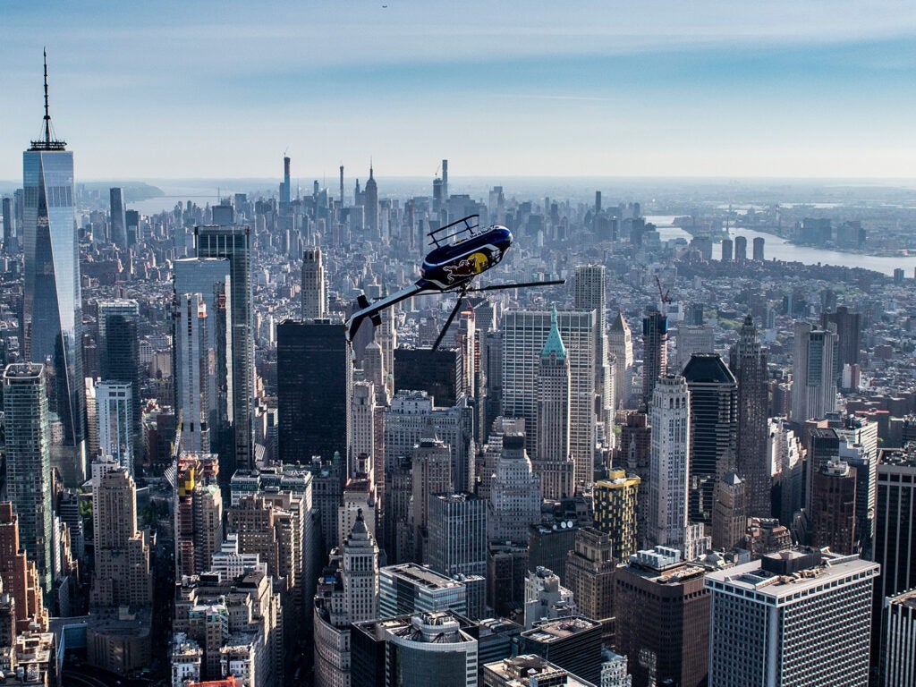 Aaron Fitzgerald in red bull helicopter inverted over the New York City skyline