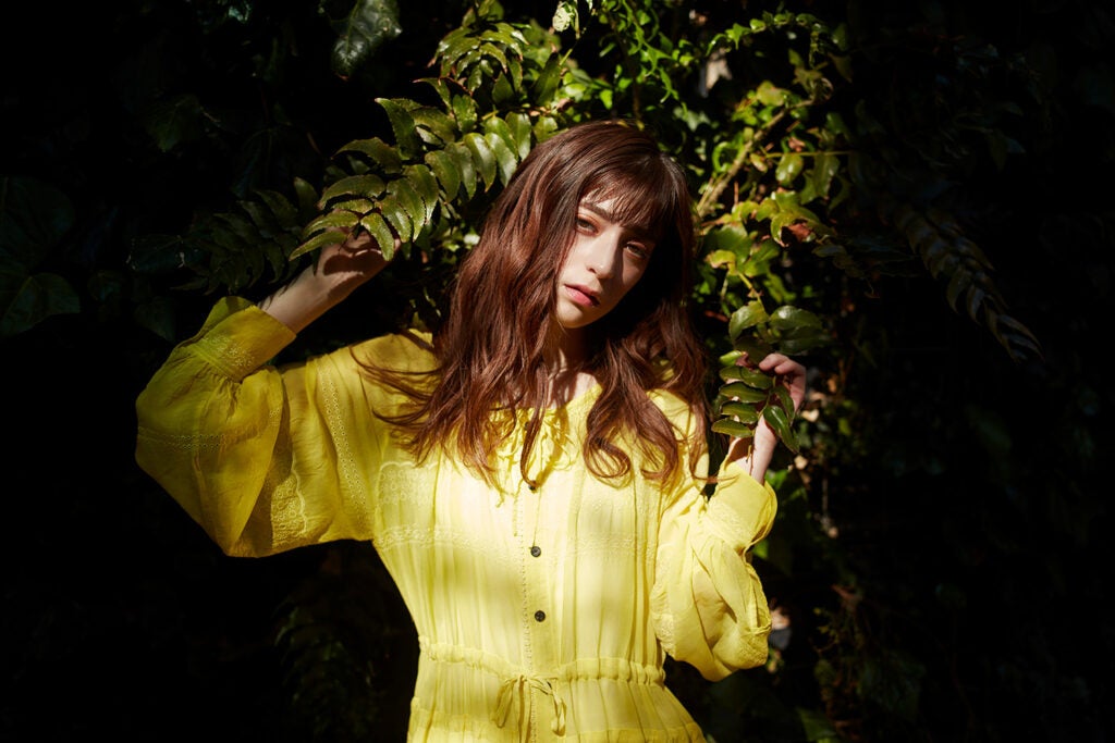 girl against greenery with yellow dress