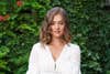 woman in white blouse against leafy backdrop