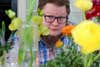 man looking at camera from behind flowers