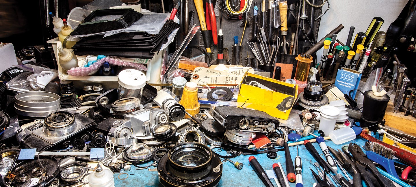 Husks of vintage film cameras and lenses littering workbench