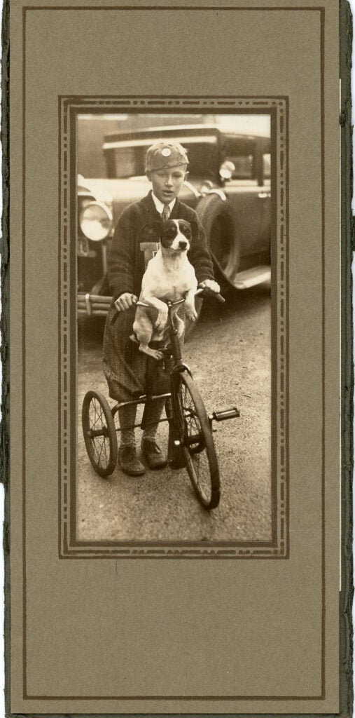 child and dog riding tricycle