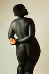 dark skinned woman holding fruit behind her back