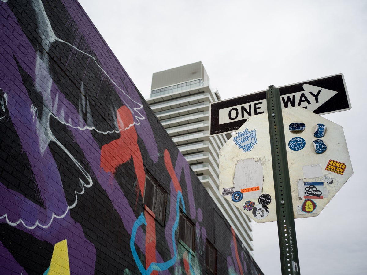 One way sign next to wall covered in graffiti