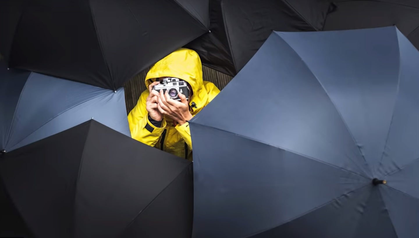 photography umbrellas around photographer in rain coat