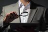 a man in a gray suit using a magnifying glass to look at a tablet